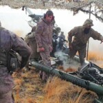 Tossing away the hot and still smoking cartridge just ejected from the gun immediately after firing. Gun commander at far left checking the fuze and propellant charge of the next shell to be fired.