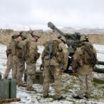163 Bty gun crew, possibly praying for a break in the weather